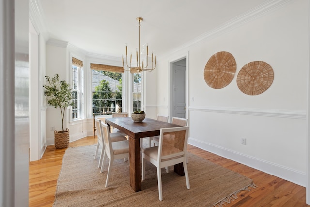 dining area with a notable chandelier, crown molding, light wood-type flooring, and baseboards