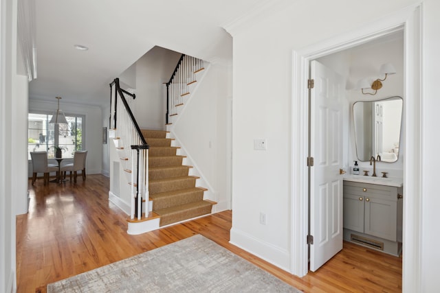 stairs with visible vents, ornamental molding, baseboards, and wood finished floors