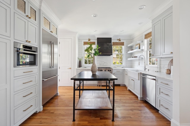 kitchen featuring a sink, tasteful backsplash, stainless steel appliances, light wood-style floors, and light countertops