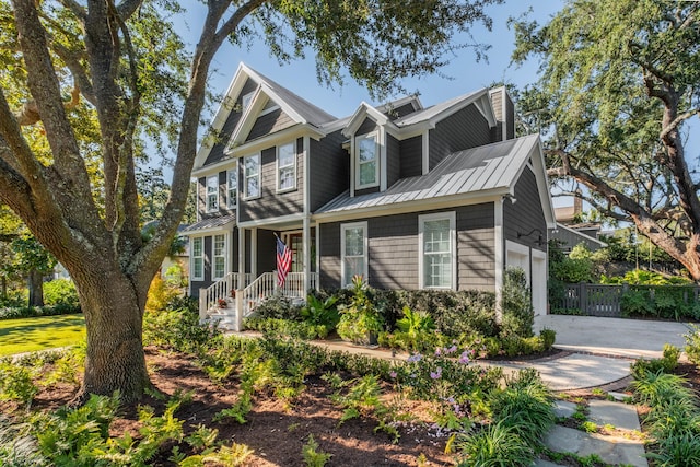 view of front of home featuring fence, driveway, a standing seam roof, a garage, and metal roof