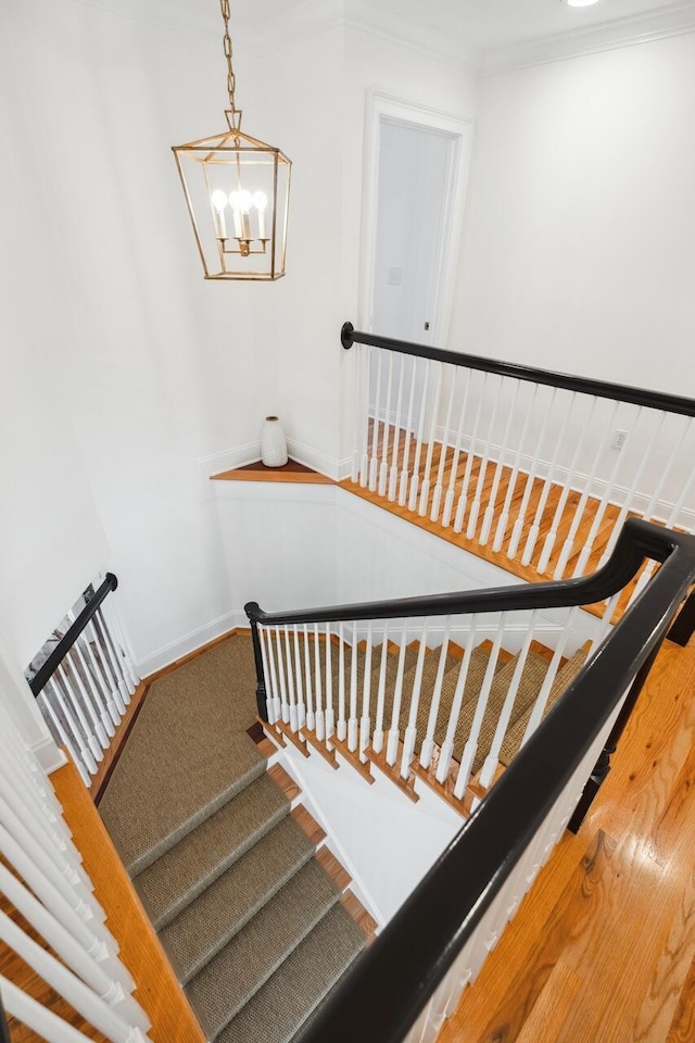 staircase featuring an inviting chandelier, baseboards, and ornamental molding