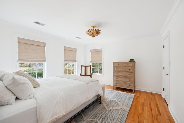 bedroom with visible vents, baseboards, light wood-style flooring, and crown molding