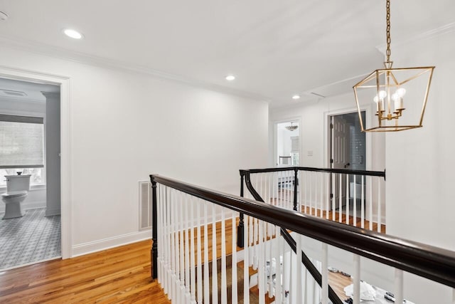 corridor with crown molding, baseboards, attic access, light wood-type flooring, and an upstairs landing