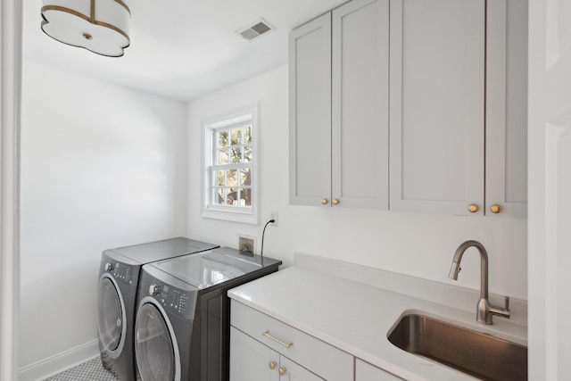 washroom with baseboards, visible vents, separate washer and dryer, cabinet space, and a sink