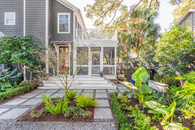 rear view of property featuring a balcony and a sunroom