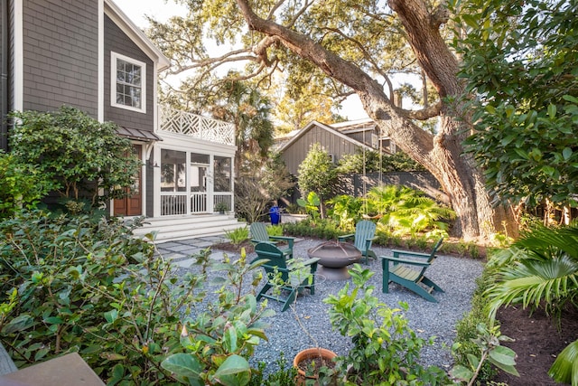 exterior space featuring a fire pit, fence, and a sunroom