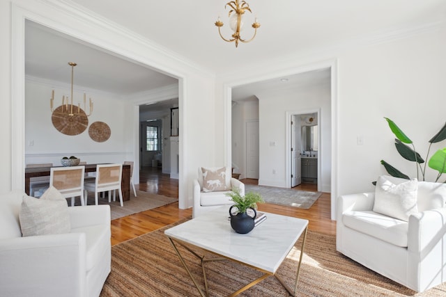 living area with an inviting chandelier, crown molding, and light wood finished floors