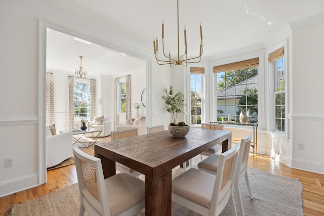 dining area featuring light wood-style floors, a notable chandelier, and crown molding