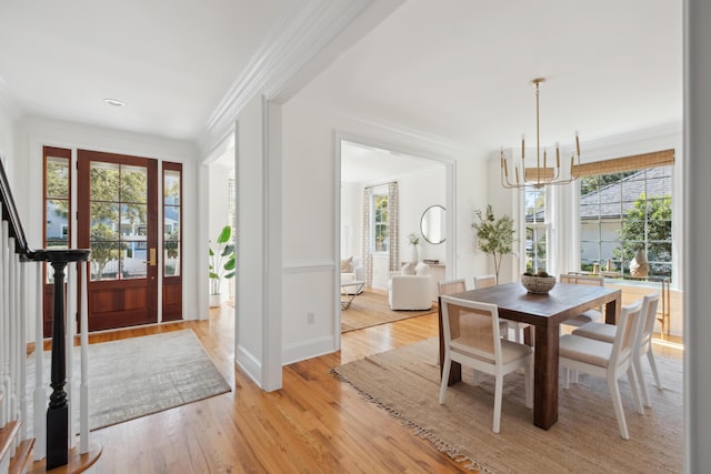 entryway featuring a chandelier, stairs, light wood-style floors, and ornamental molding