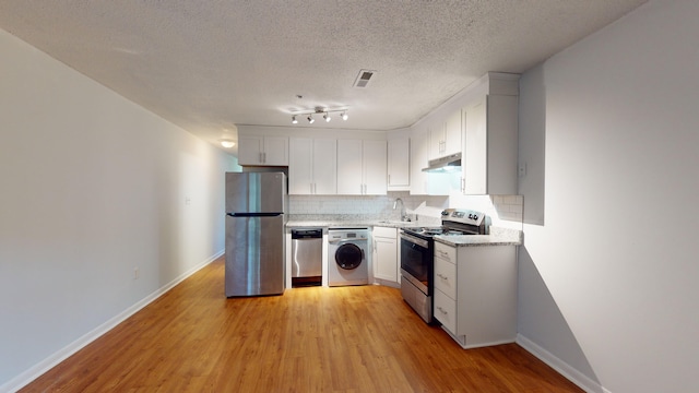 kitchen featuring appliances with stainless steel finishes, sink, light wood-type flooring, and washer / clothes dryer