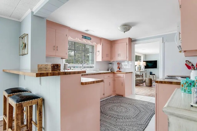 kitchen with a breakfast bar, sink, crown molding, decorative backsplash, and kitchen peninsula