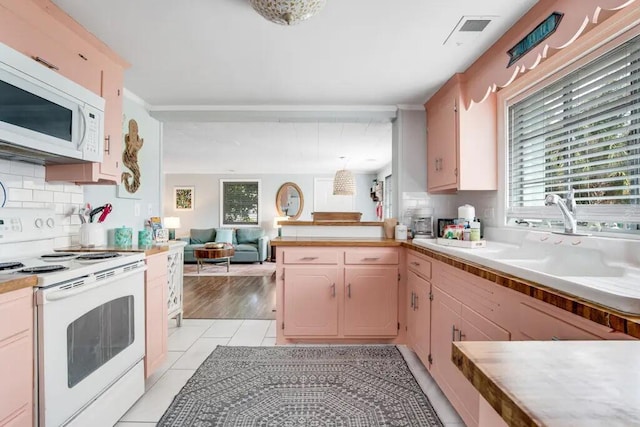 kitchen featuring tasteful backsplash, white appliances, sink, light tile patterned floors, and pendant lighting