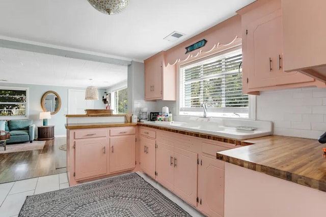 kitchen with kitchen peninsula, backsplash, sink, and light tile patterned flooring