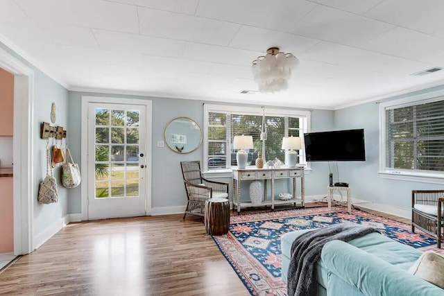 living room with light wood-type flooring and ornamental molding