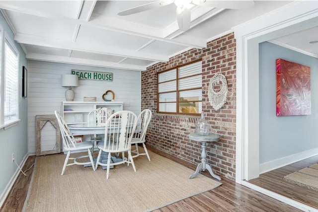 dining area with hardwood / wood-style flooring, beamed ceiling, brick wall, and coffered ceiling