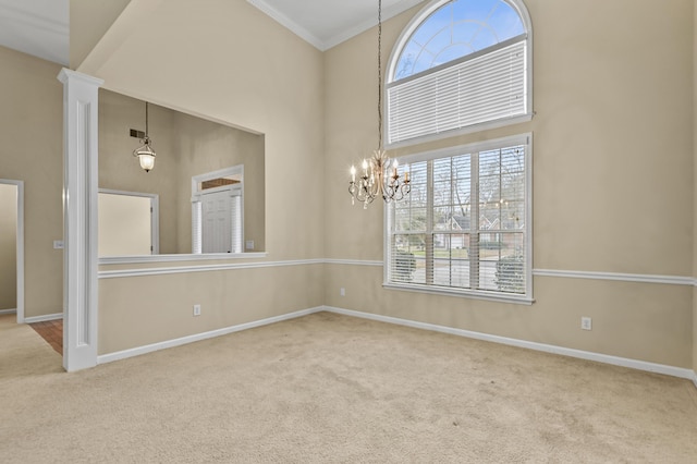 carpeted empty room with plenty of natural light, a towering ceiling, baseboards, and an inviting chandelier