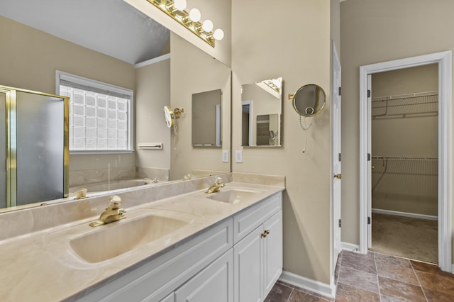 bathroom with baseboards, a spacious closet, a sink, and a shower stall