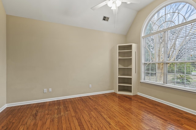 spare room featuring visible vents, vaulted ceiling, ceiling fan, wood finished floors, and baseboards