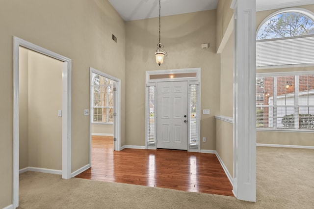 entrance foyer with light wood-style floors, baseboards, and light colored carpet