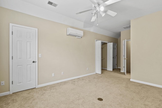 unfurnished bedroom with a wall mounted air conditioner, visible vents, light carpet, and baseboards