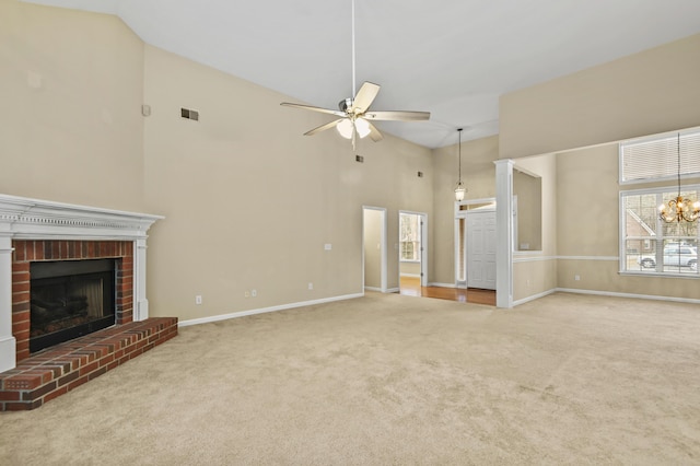 unfurnished living room with ceiling fan with notable chandelier, carpet flooring, visible vents, baseboards, and a brick fireplace