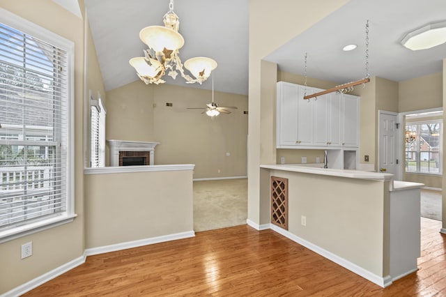 kitchen featuring light countertops, light wood-type flooring, a brick fireplace, and white cabinets