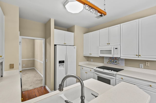 kitchen with white appliances, a sink, baseboards, white cabinets, and light countertops