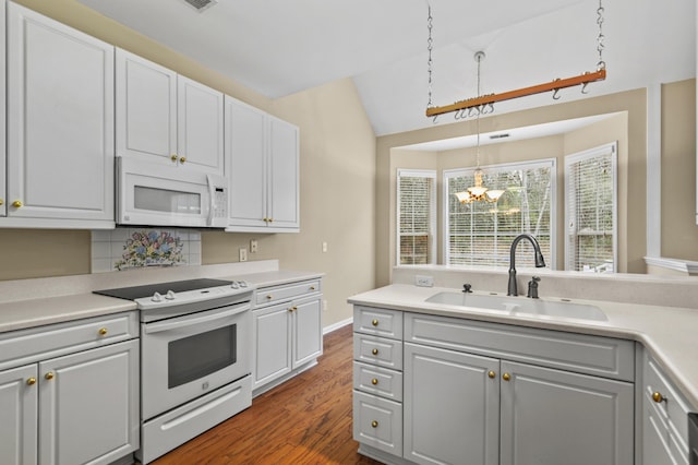 kitchen featuring light countertops, white appliances, a sink, and decorative light fixtures