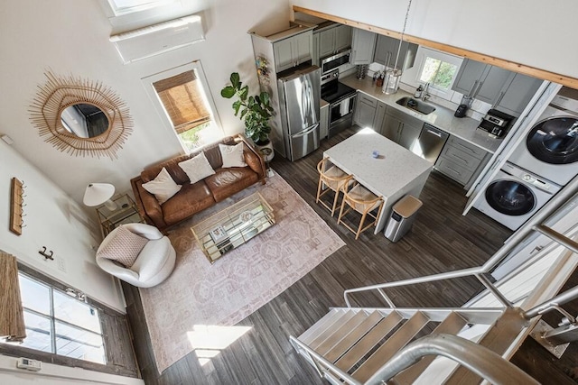 living area with stacked washer / drying machine and dark wood-style floors