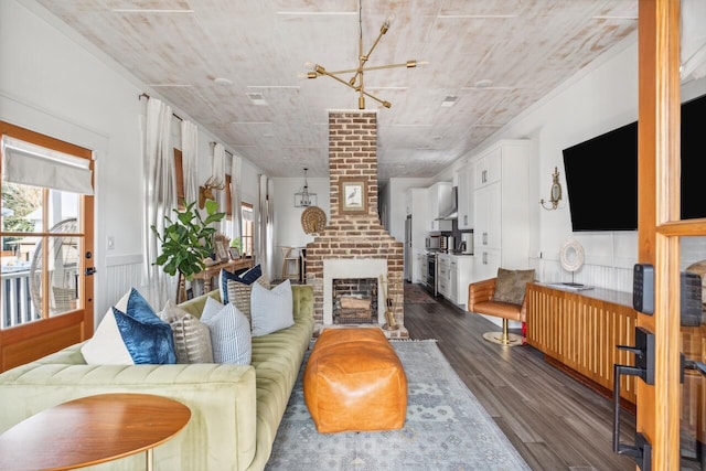 living room featuring dark wood finished floors, a brick fireplace, and a chandelier