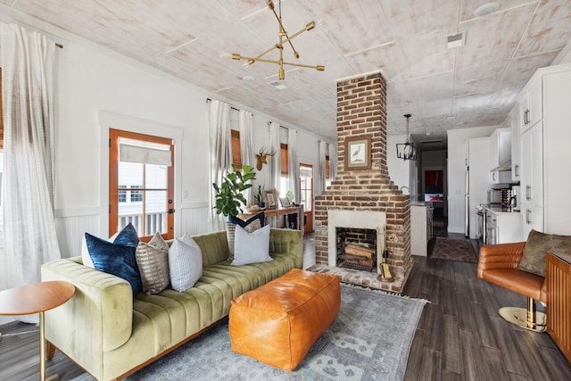 living room with dark wood-style flooring, a chandelier, and a wainscoted wall