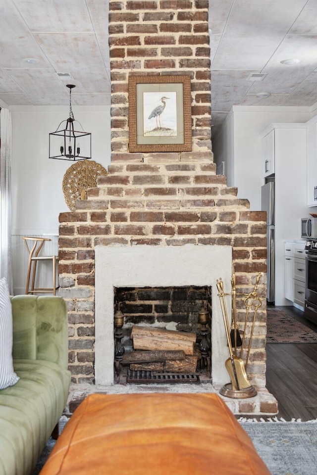 detailed view of appliances with stainless steel finishes, wood finished floors, a fireplace, and a chandelier