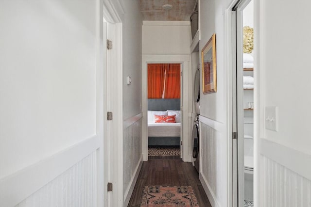 hall with dark wood finished floors and stacked washer / drying machine