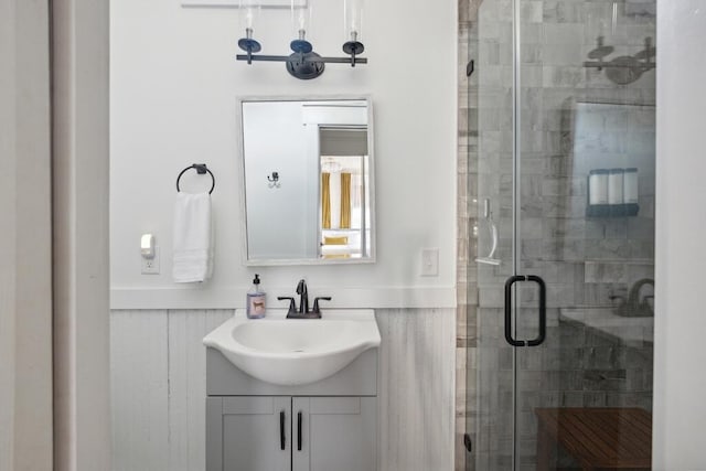 full bathroom featuring vanity, a stall shower, and a wainscoted wall