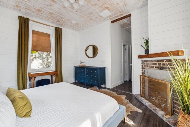 bedroom with a fireplace, wooden walls, and wood finished floors