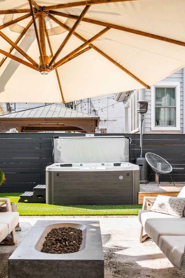 view of patio featuring a hot tub, a fire pit, and fence