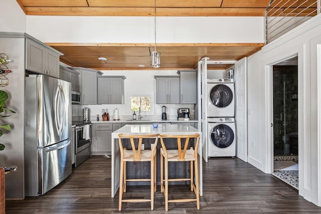 kitchen featuring appliances with stainless steel finishes, stacked washer / drying machine, gray cabinetry, and a sink