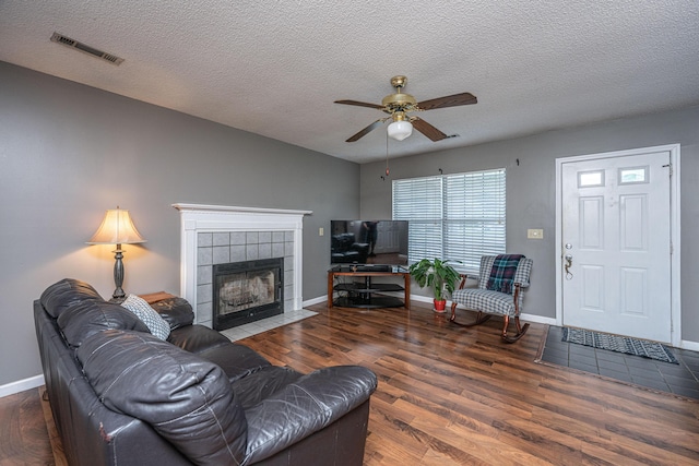 living area with visible vents, wood finished floors, baseboards, a textured ceiling, and a ceiling fan