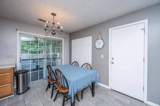 dining area featuring visible vents, a textured ceiling, baseboards, and a notable chandelier