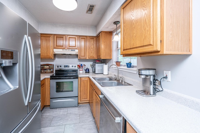 kitchen featuring visible vents, appliances with stainless steel finishes, a sink, light countertops, and under cabinet range hood
