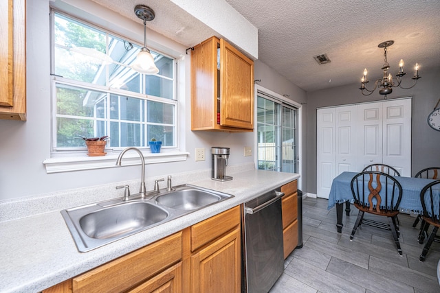 kitchen with visible vents, light countertops, a sink, dishwasher, and decorative light fixtures