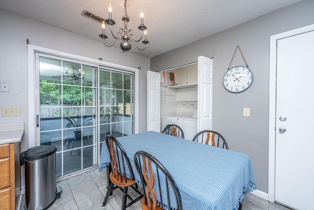 dining area featuring visible vents, a textured ceiling, a notable chandelier, and washer / dryer