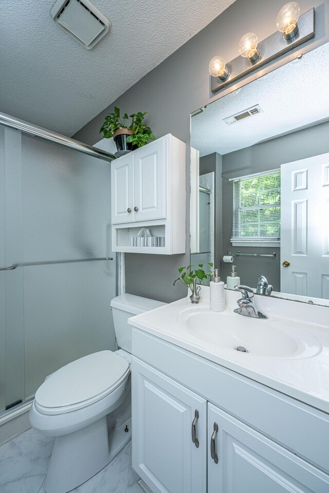 bathroom with vanity, toilet, a textured ceiling, marble finish floor, and a stall shower