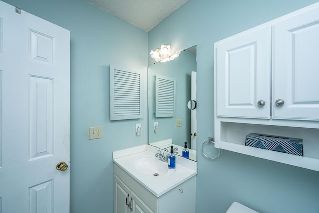 bathroom with vanity, toilet, and a textured ceiling