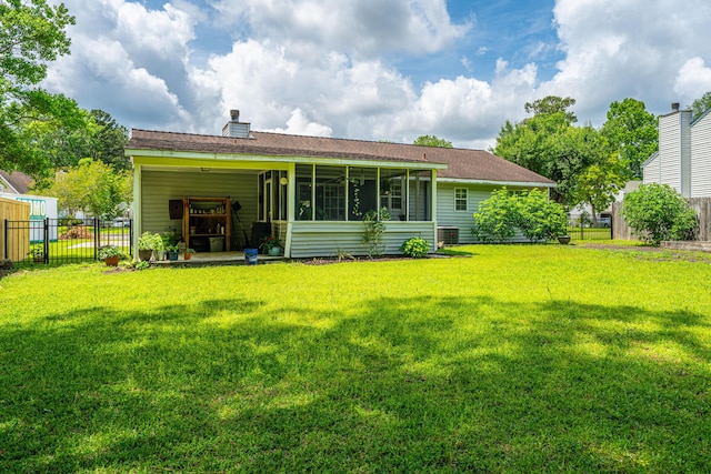 rear view of house with fence, a shingled roof, a sunroom, a chimney, and a lawn