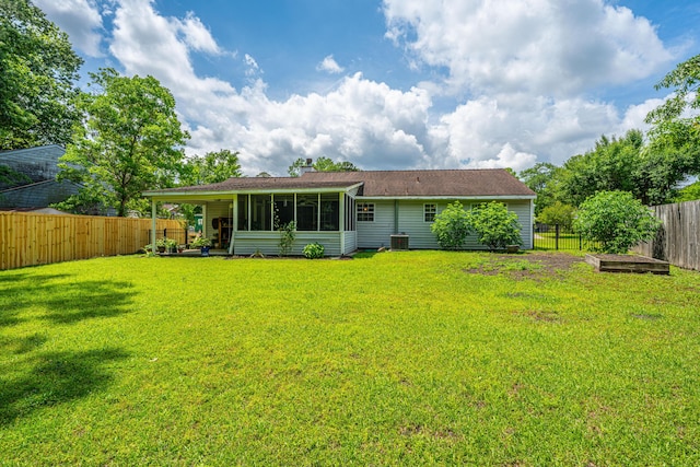 rear view of house featuring a lawn, a fenced backyard, and a sunroom