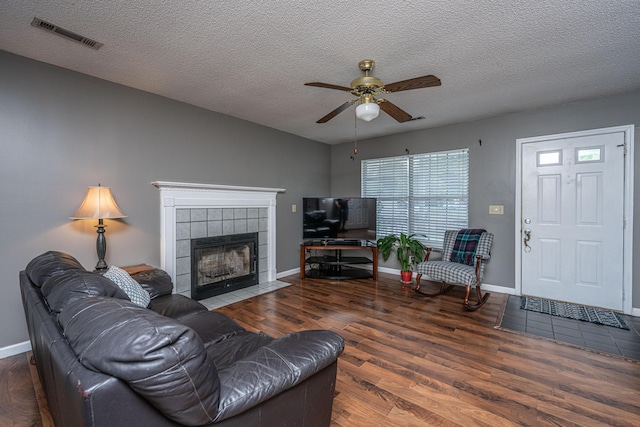 living room with a ceiling fan, a textured ceiling, visible vents, and wood finished floors