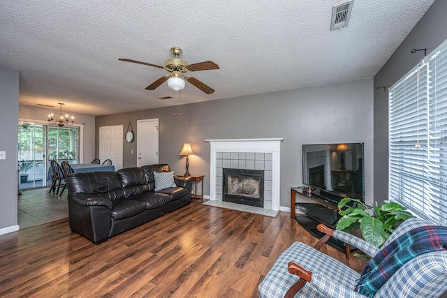 living room with visible vents, a textured ceiling, ceiling fan with notable chandelier, and wood finished floors