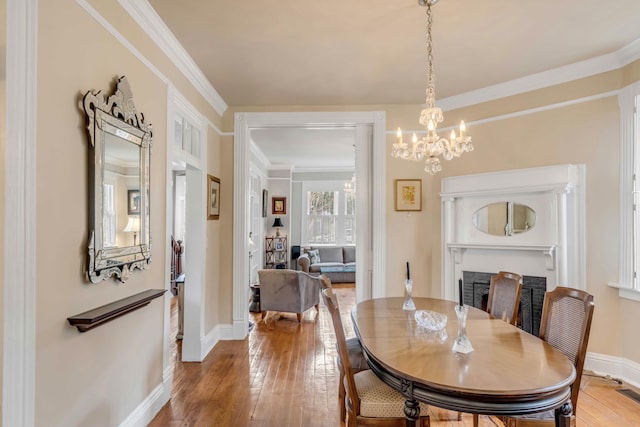 dining room featuring hardwood / wood-style floors, ornamental molding, and a notable chandelier