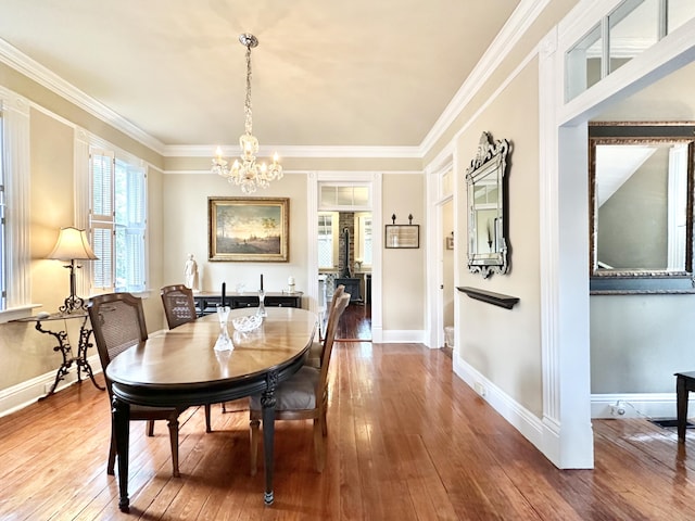 dining space with hardwood / wood-style flooring, an inviting chandelier, and crown molding